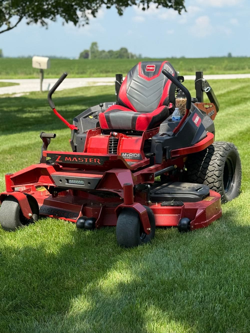 Zero-turn mower on a well-manicured lawn with a countryside backdrop.