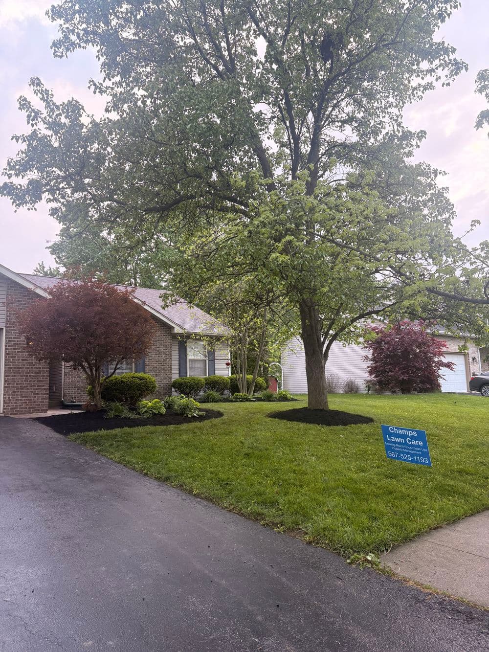 House with well-maintained lawn, flower beds, and "Change Lawn Care" sign in front yard.