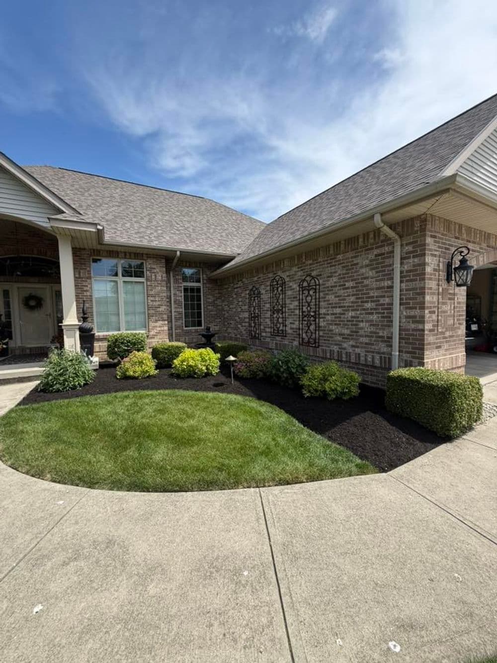 Brick house with well-maintained landscaping and a clear blue sky.