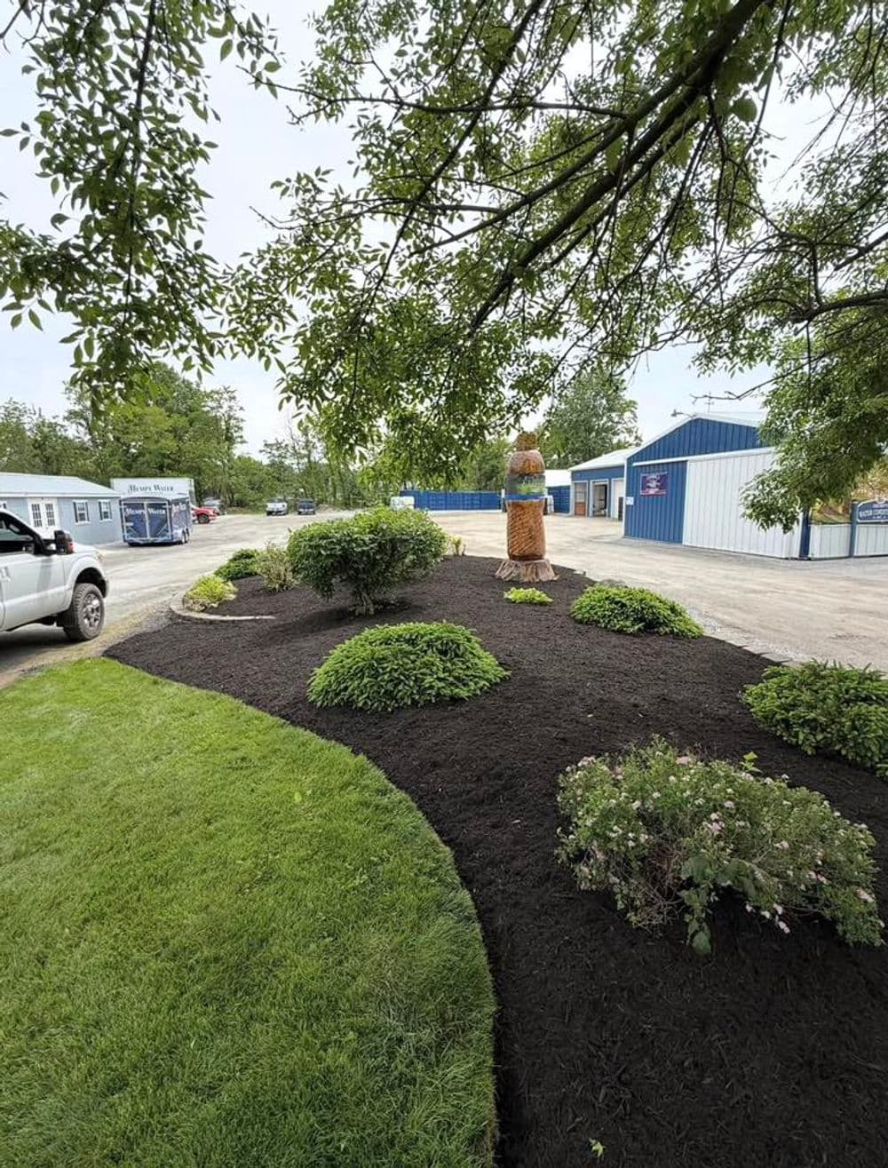 Lush landscaped area featuring a tree and decorative statue near a storage facility.